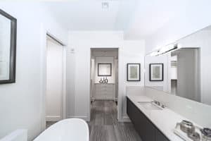 This image features a master bathroom with a white claw tub across from the sink. 