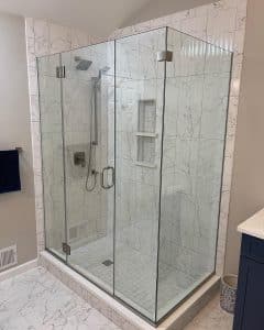 Open shower that is surrounded by white, marbled tile.