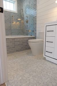 White bathroom with a shower that feature grey tiles. 